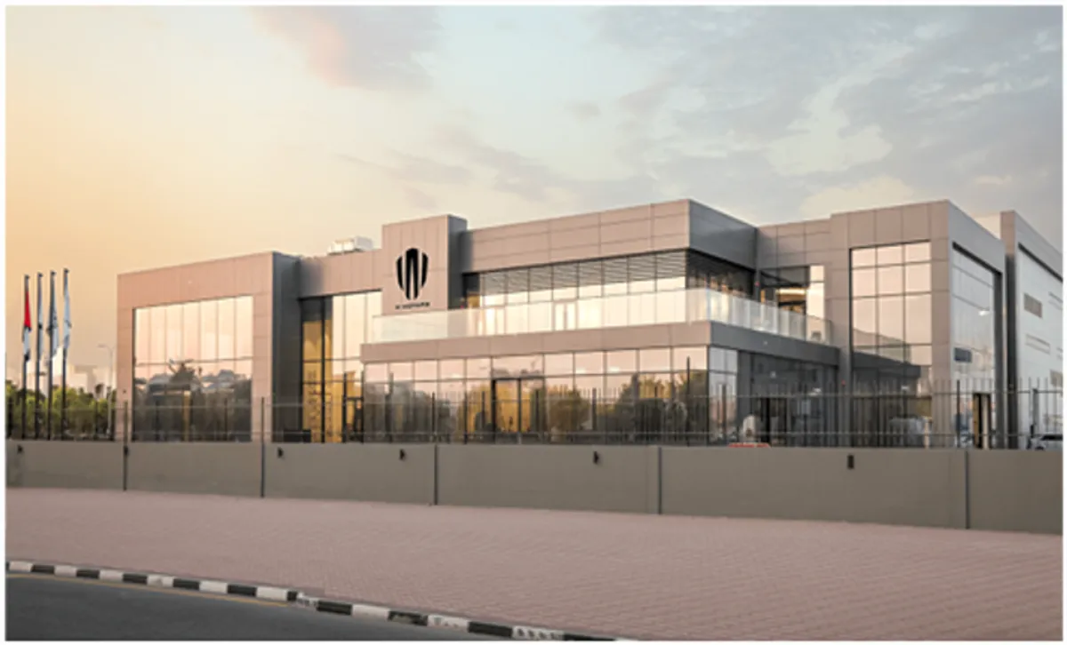 A smiling man in a suit with his arms crossed, standing outdoors.