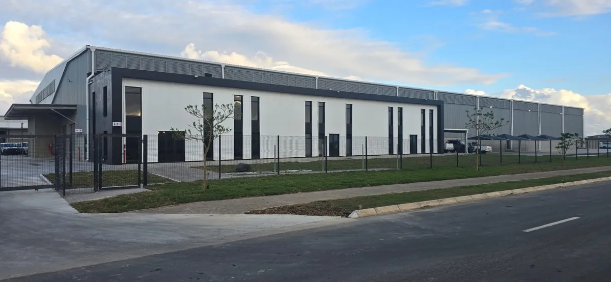 A smiling man in a suit with his arms crossed, standing outdoors.