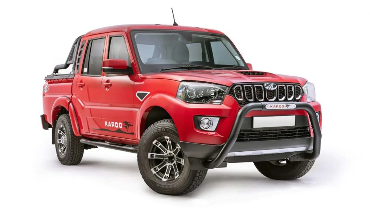 A smiling man in a suit with his arms crossed, standing outdoors.